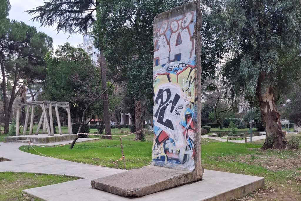 חתיכה חלק מחומת ברלין שתרמה גרמניה לאלבניה באנדרטת הצ'ק פוינט בטירנה ועמודי כרייה ממחנה השמדה של אסירים פולטיים